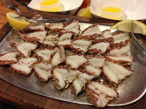 A silver platter filled with cooked lobster tails, garnished with lemon wedges.