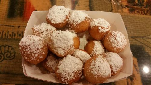 A box of small, round doughnuts dusted with powdered sugar, arranged neatly on a table.