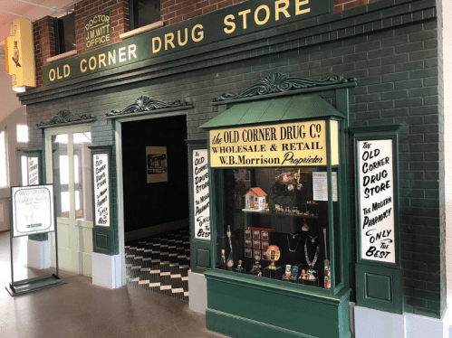 Historic storefront of the Old Corner Drug Store, featuring a display window and vintage signage.