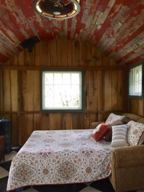 Cozy room with a wooden ceiling, a bed with a patterned quilt, and a window letting in natural light.
