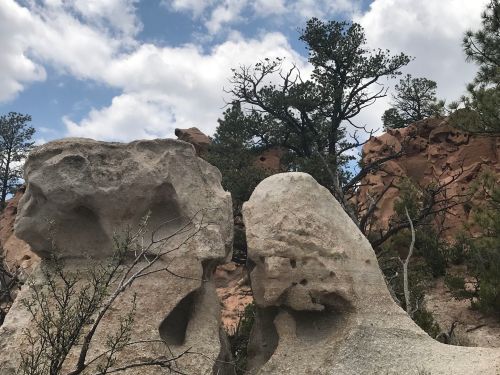 Two large rock formations surrounded by trees and a cloudy sky, showcasing unique natural shapes and textures.