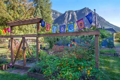 A vibrant garden with colorful flags, surrounded by lush greenery and mountains in the background.