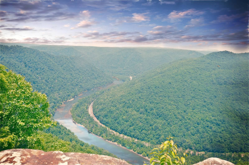 A scenic view of a winding river surrounded by lush green mountains under a cloudy sky.