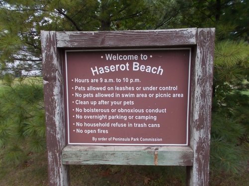 Sign at Haserot Beach with rules: hours, pet policies, conduct guidelines, and waste disposal instructions.