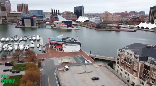Aerial view of a waterfront area with boats, buildings, and a marina in an urban setting.