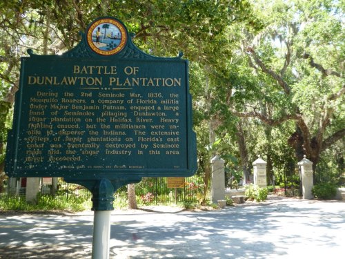 Historical marker about the Battle of Dunlawton Plantation during the Second Seminole War, surrounded by trees.