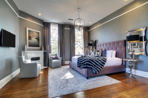 Modern bedroom with a large bed, stylish decor, a cozy armchair, and a window letting in natural light.