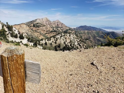 A wooden post in the foreground with a mountainous landscape and blue sky in the background.