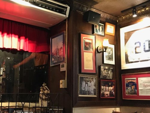 Cozy restaurant interior featuring framed photos, memorabilia, and a red curtain, creating a warm atmosphere.