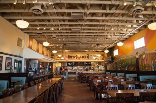 Interior of Joe's Red B-B-Q, featuring wooden tables, a vibrant mural, and a spacious dining area.
