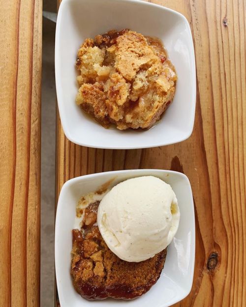 Two bowls of dessert: one with warm cobbler and the other with cobbler topped with a scoop of vanilla ice cream.