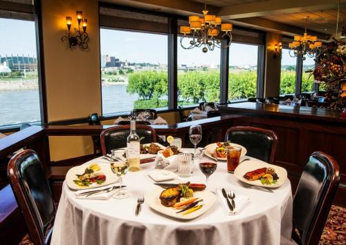 Elegant dining table set with gourmet dishes, wine, and a view of the river through large windows.