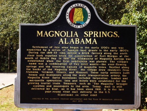 Sign about Magnolia Springs, Alabama, detailing its history and development from the early 1700s to the 1800s.