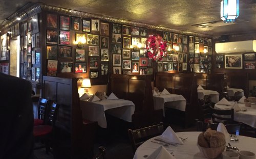 Cozy restaurant interior with wooden booths, white tablecloths, and walls adorned with framed photos and memorabilia.