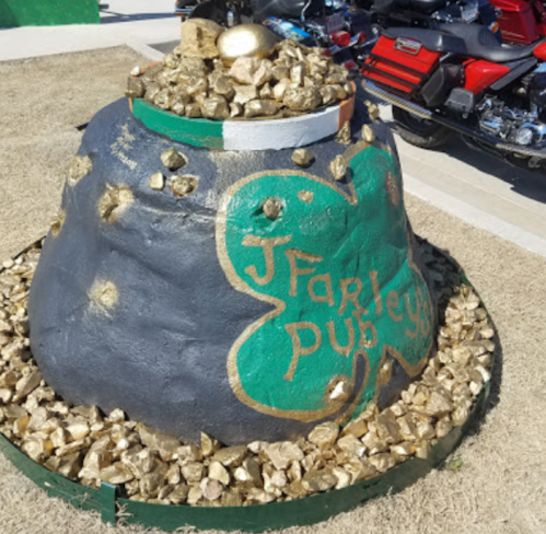 A large, painted rock resembling a pot of gold, decorated with gold stones and the text "J Farley Pub."