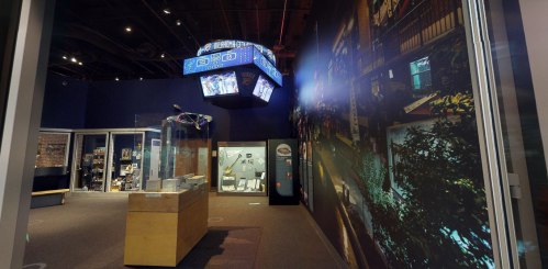 A museum interior featuring displays, a large overhead structure, and vibrant wall murals.