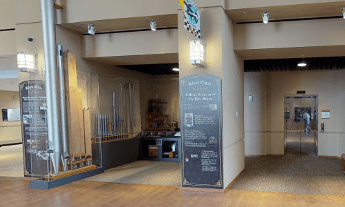 Interior view of a museum featuring a pipe organ display and informational panels about its history.