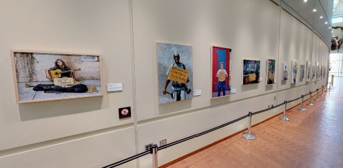 A gallery wall displaying various framed photographs of people, with a mix of colors and subjects.