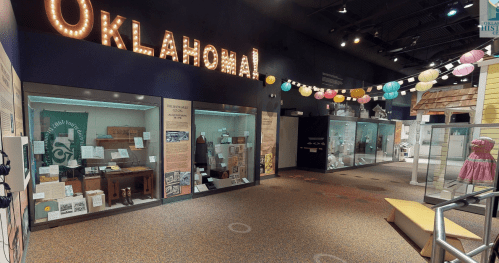Exhibit space in a museum featuring displays about Oklahoma's history, with colorful lanterns overhead.