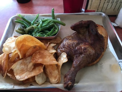 A tray with roasted chicken, crispy potato chips, and a side of green beans.
