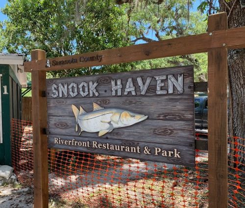 Sign for Snook Haven Riverfront Restaurant & Park in Sarasota County, featuring a carved fish design.