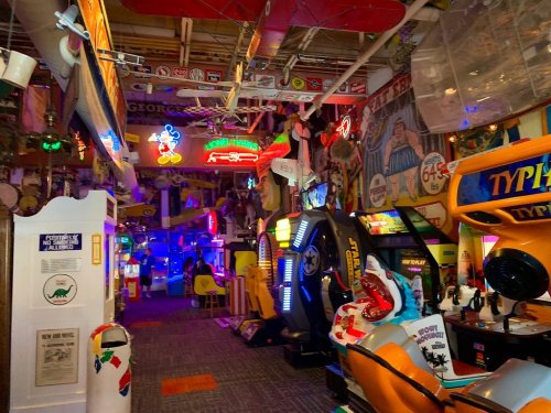 A vibrant arcade filled with colorful neon lights, vintage games, and eclectic decor, creating a lively atmosphere.
