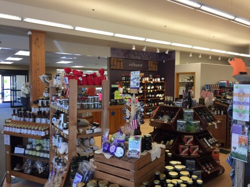Interior of a store featuring shelves of wine, jars of preserves, and various local products, with a welcoming atmosphere.