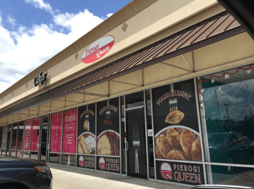 Exterior of a storefront featuring "Pierogi Queen" and "Polish Cuisine" signs, with a clear blue sky above.