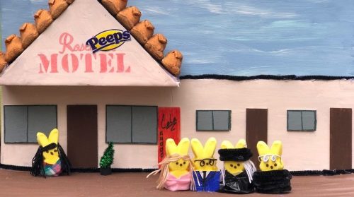 A colorful model of a motel with Peeps marshmallow figures dressed in various outfits in front.