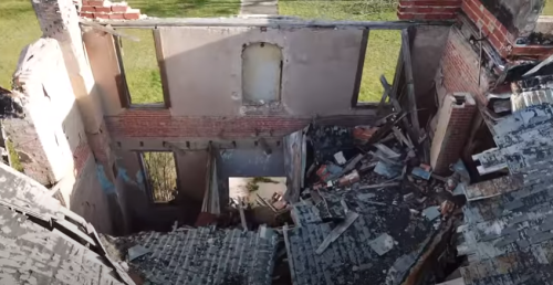 Aerial view of a dilapidated building with collapsed walls and debris scattered on the floor.