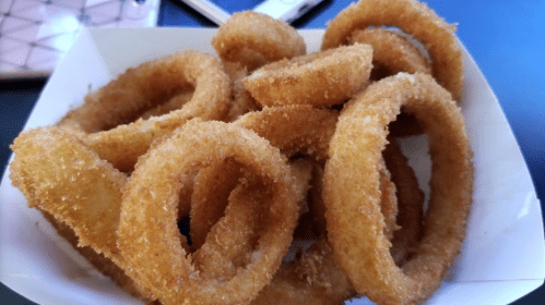 A close-up of a bowl filled with golden, crispy onion rings.