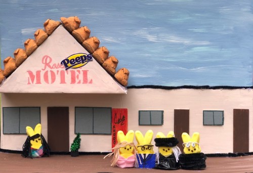A colorful model of a motel made from Peeps, featuring four Peeps dressed in various outfits in front of the building.