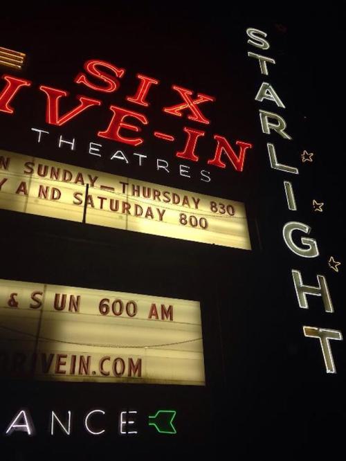 Neon sign for Starlight Six Drive-In Theatres, displaying showtimes and website information.