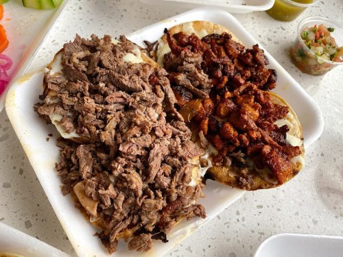 A plate with two tortillas topped with shredded beef and diced pork, served with fresh salsa on the side.