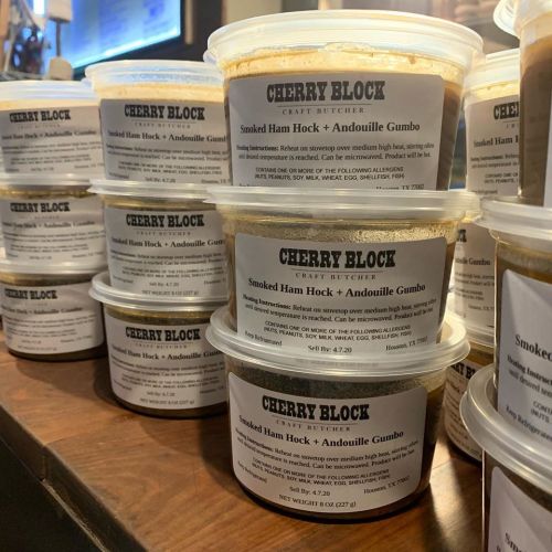 Containers of Cherry Block's Smoked Ham Hock & Andouille Gumbo stacked on a counter.
