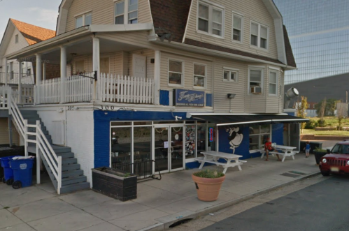 A two-story building with a blue and white exterior, featuring a storefront and outdoor seating area.