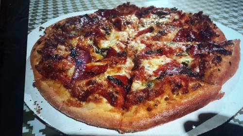 A freshly baked pizza topped with pepperoni, cheese, and herbs on a white cardboard base.
