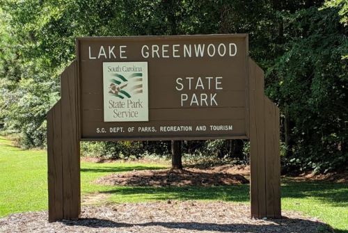 Sign for Lake Greenwood State Park in South Carolina, featuring the state park logo and information about the park services.