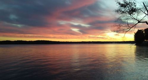 A serene lake at sunset, with vibrant pink and purple clouds reflecting on the water's surface.
