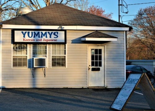 Exterior of a small restaurant named "Yummys," featuring a sign for Korean and Japanese cuisine.