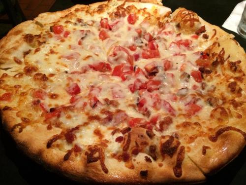 A freshly baked pizza topped with melted cheese and diced tomatoes on a golden crust.