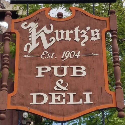 Sign for Kurtz's Pub & Deli, established in 1904, featuring a wooden design with decorative elements.