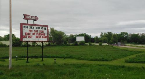 Sign for Big Sky Theatre advertising movies "Fate of the Furious," "Get Out," and "Boss Baby," set in a grassy area.