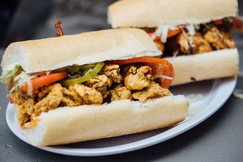 Two crispy fried chicken sandwiches with lettuce, tomato, and pickles, served on a white plate.