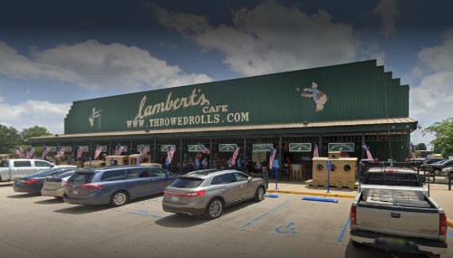 Exterior of Lambert's Cafe with cars parked outside, featuring a green building and a sign for "threwed rolls."