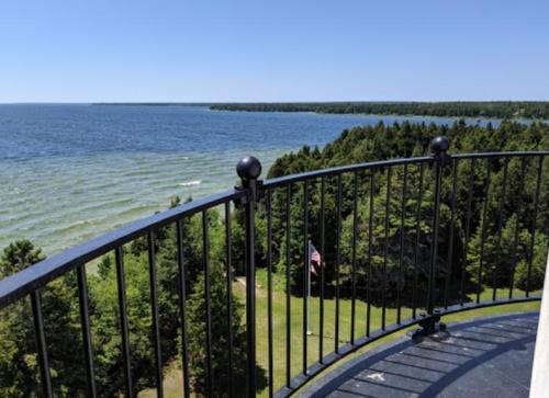 View from a lighthouse balcony overlooking a blue lake and green trees under a clear sky.
