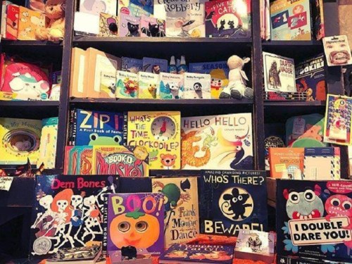 A colorful bookshelf filled with children's books, toys, and playful decorations.