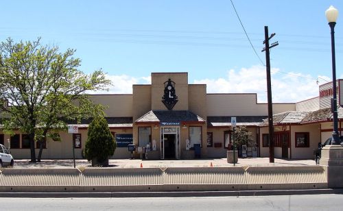 A building with a distinctive logo, featuring a tree in front and a clear blue sky above.