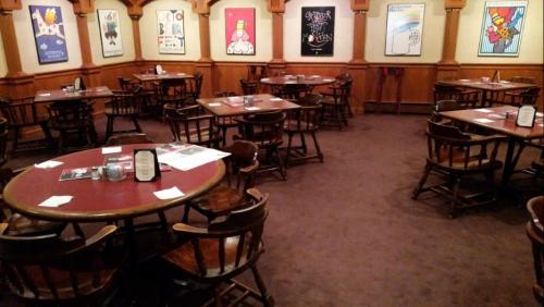 A cozy restaurant interior with wooden tables and chairs, featuring colorful wall art and a warm atmosphere.