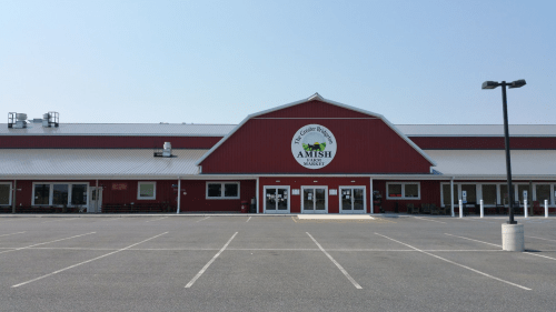 A large red barn-style building with a sign reading "Amish Market" and a mostly empty parking lot.